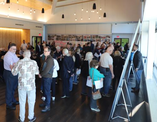 Photo of Prairie Village Community Center Campus Study public meeting on April 4, 2024. Guests look at boards with potential site configuration plans and talk with other guests and representatives from partners.