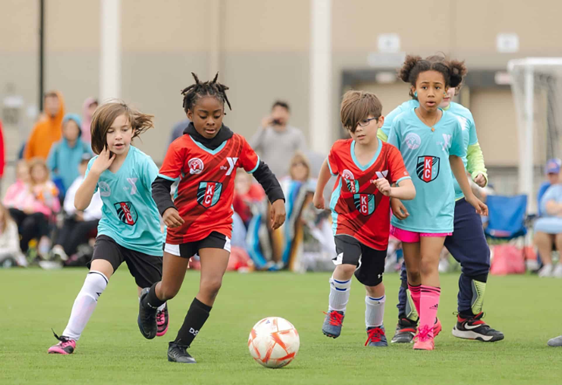 Children playing in a YMCA youth soccer game on a turf field