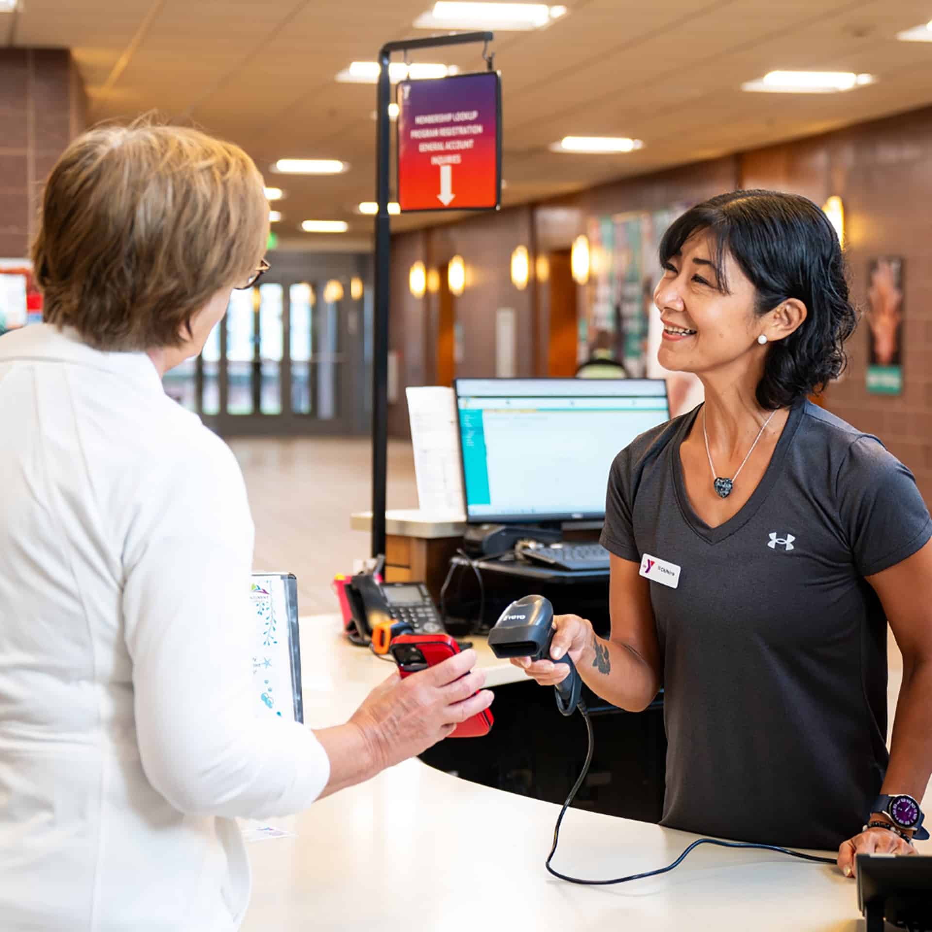 YMCA staff member scanning a member's card at a YMCA front desk