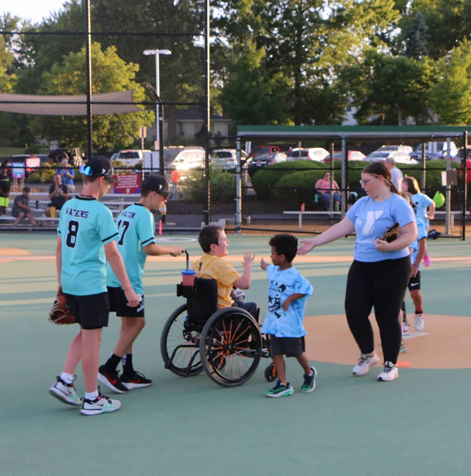 Children and teens including a child using a wheelchair greeting each other at a YMCA inclusive sports event
