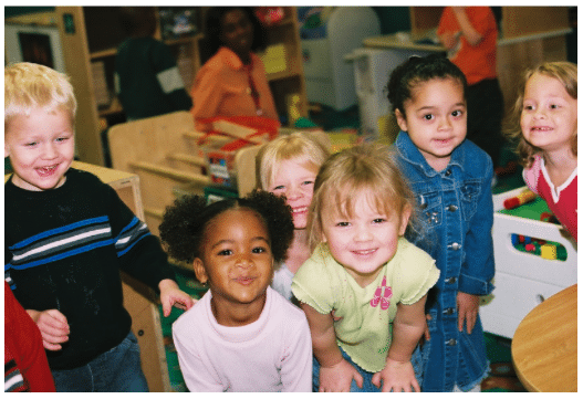 Six smiling preschool children gather in a bright early education classroom