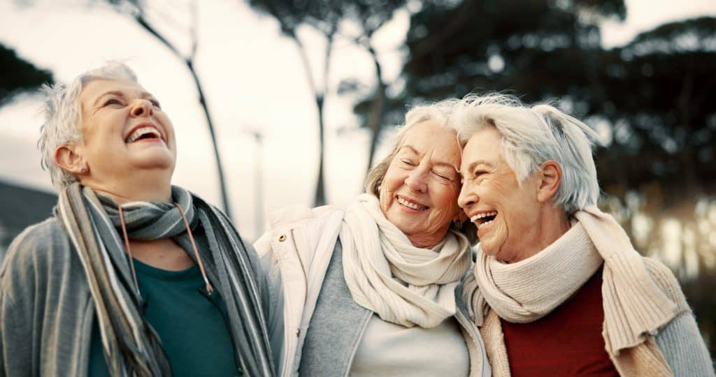 Three older women laughing together outdoors