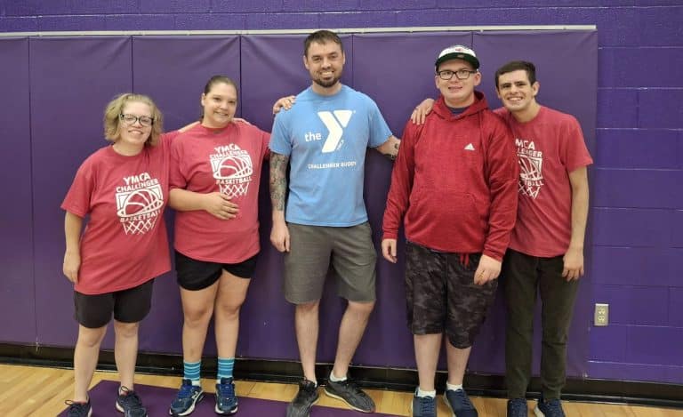 Challenger basketball athletes and volunteers posing in a YMCA gym