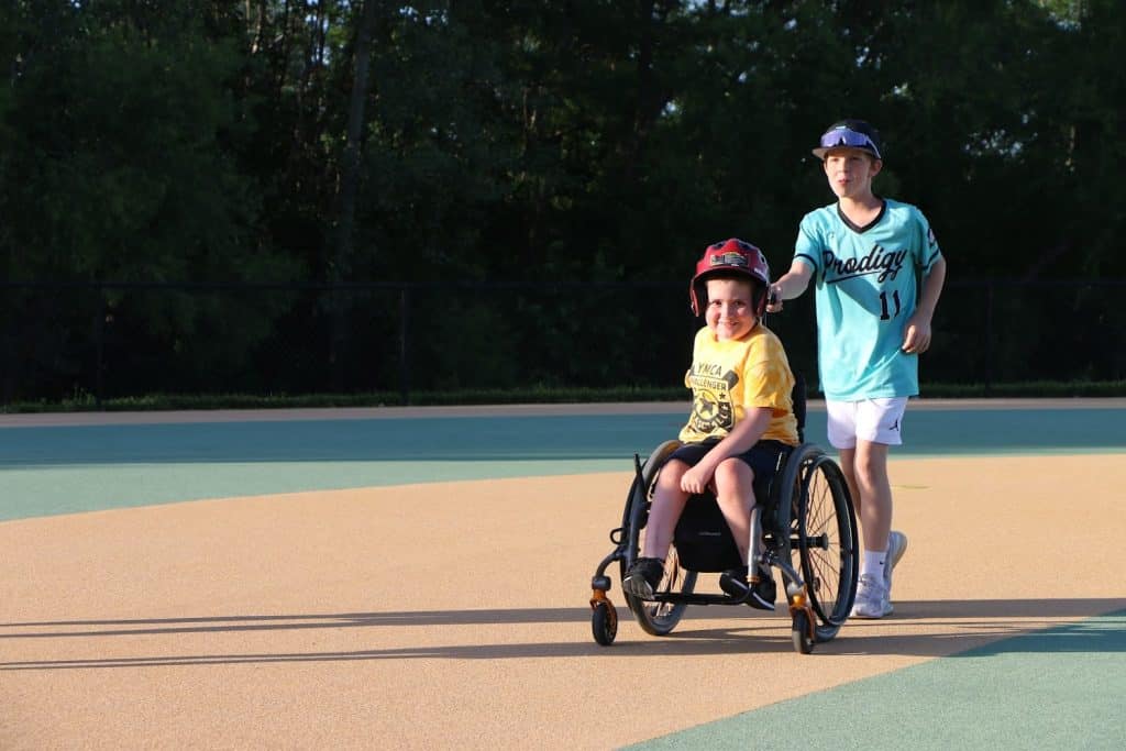 Challenger athlete in a wheelchair with a buddy on a ball field