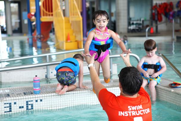 Children participating in swim lessons at an indoor pool.