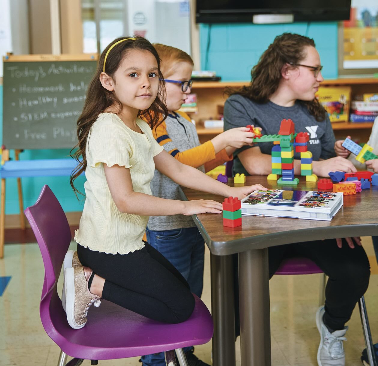 Student working on blocks with other students and staff member.