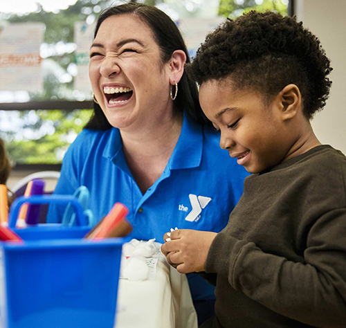 Staff member and student laughing while working on project.