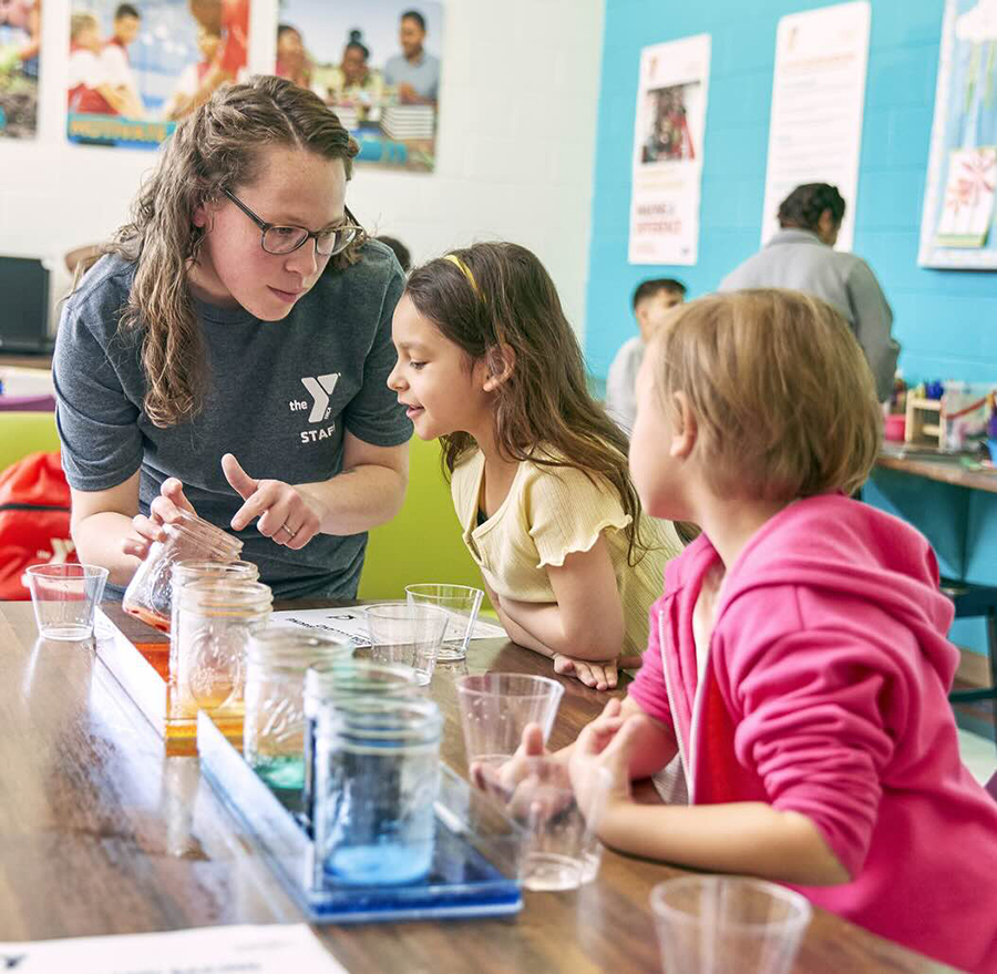 After school staff works with students on a science experiment.