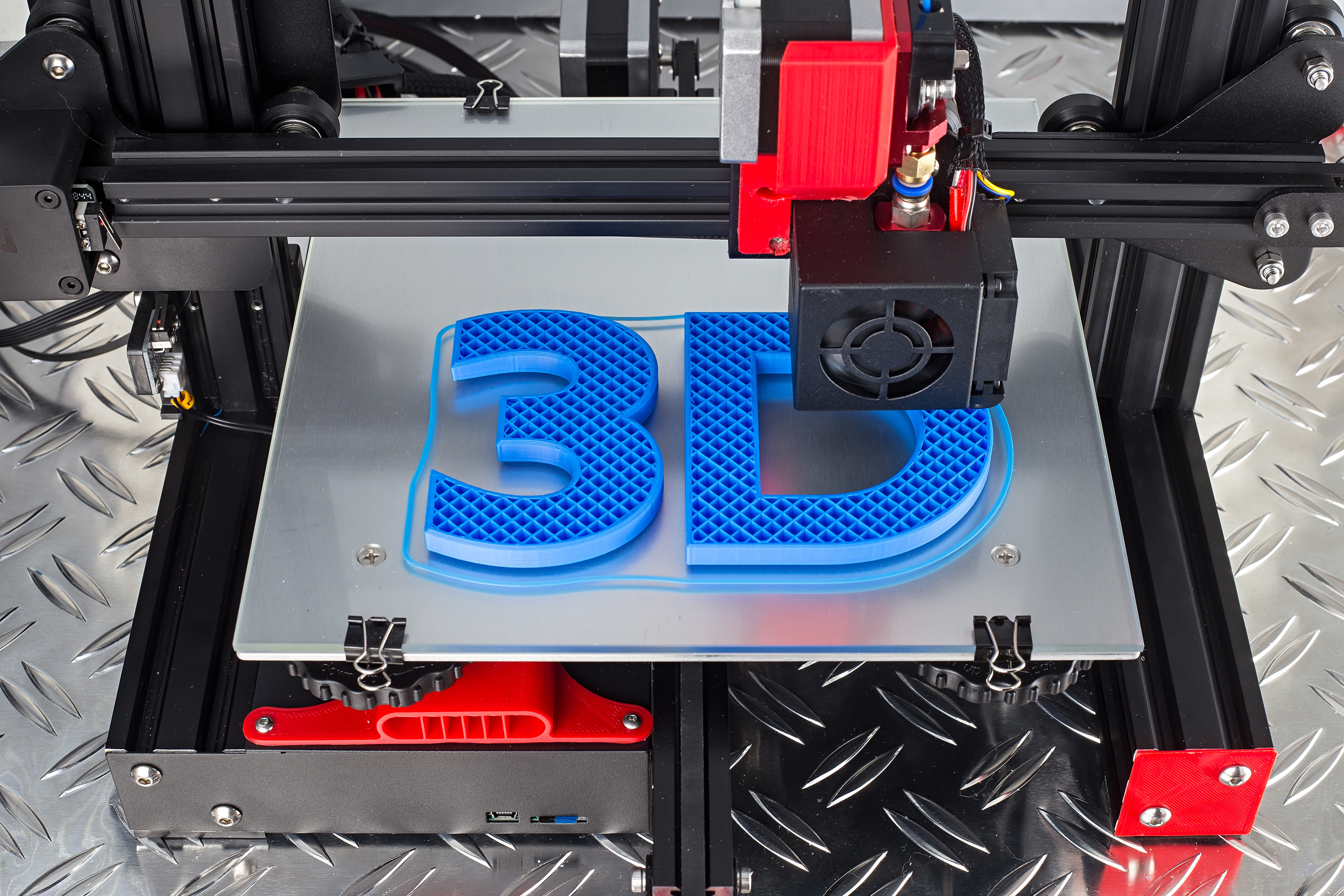 Photo of red black 3D printer printing blue logo symbol