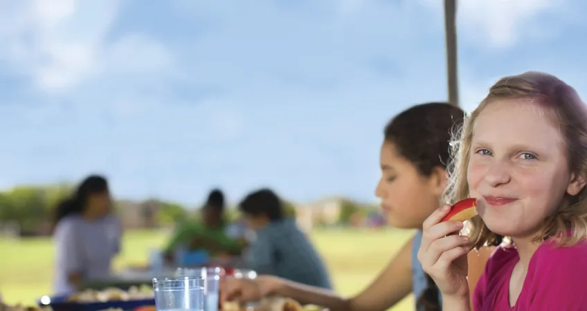 Young girl eating an apply slice in promotion of of the Nutrition Programs at the YMCA of Greater Kansas City