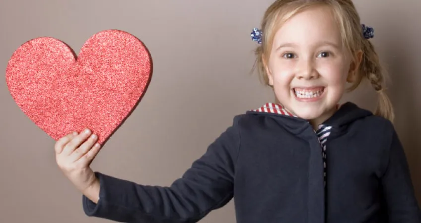 Young girl hold a glittery heart cut out in support of heart health for the Kansas City YMCA