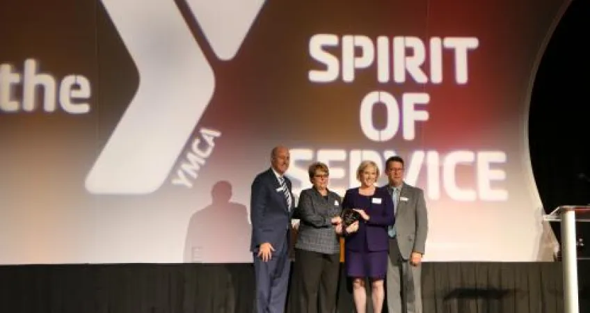 a group of four people standing on the event stage holding an award.