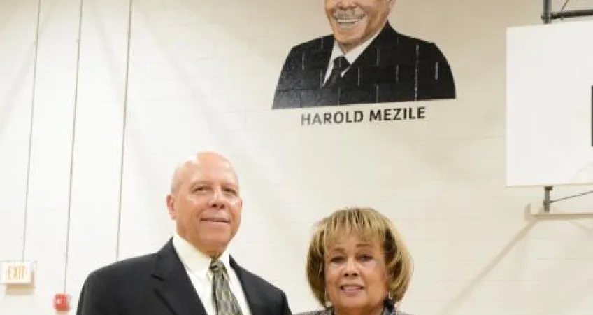 Harold and Peggye Mezile standing in front of his portrait.