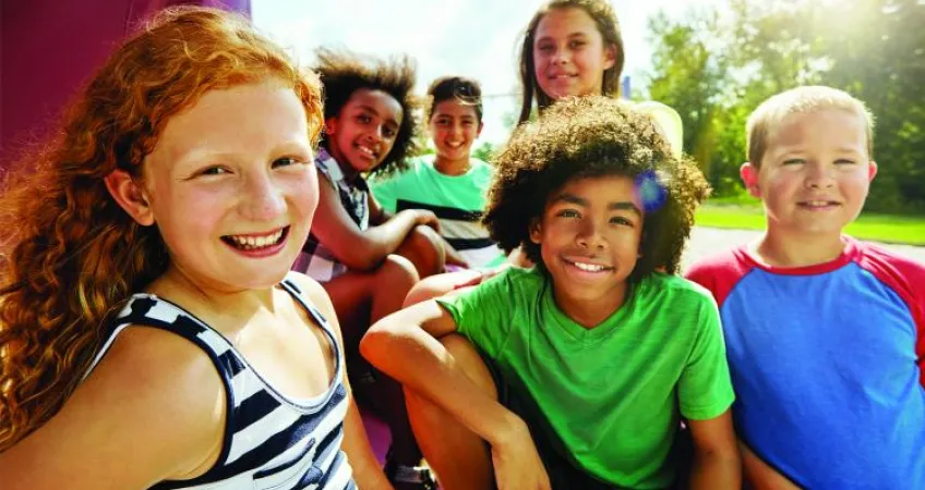 Six kids are gathered together outside smiling at the camera