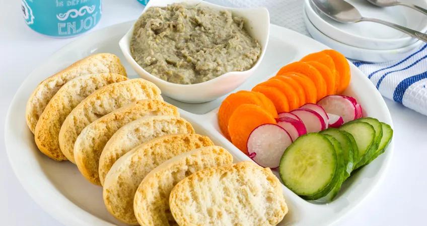 Party platter of healthy snacks including vibrant veggies, whole grain crackers, and hummus.