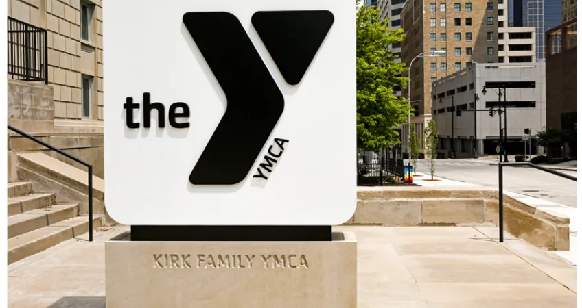 Photo of monument sign outside the Kirk Family YMCA. Include black logo on white background, with Kirk Family YMCA engraved on stone base.