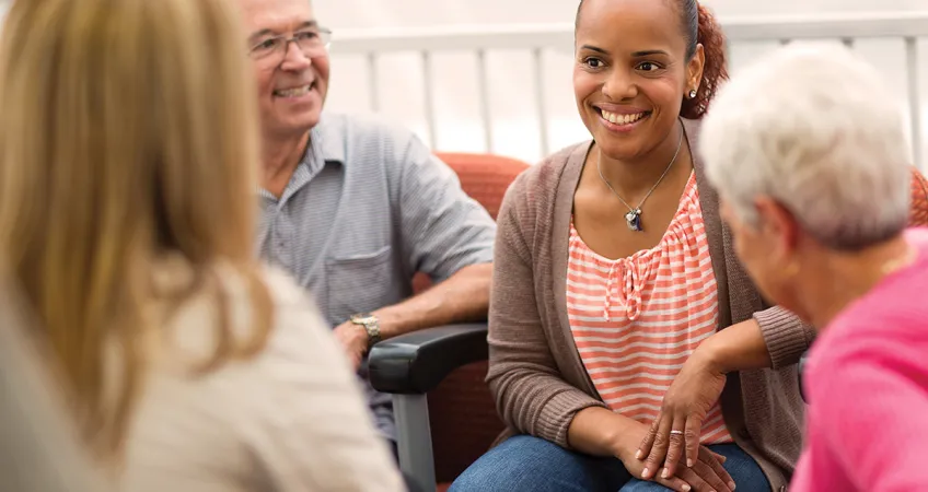 4 adults seated together smiling while talking about healthcare hosting in a Medicare Information session.