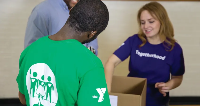 3 volunteers working the Volunteer book drive. 2 of the volunteers are wearing Greater Kansas City YMCA volunteer t-shirts.