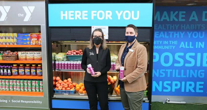 Shari Coulter Ford, Tohi Beverages, and Tina Weaver, North Kansas City YMCA Executive Director, hold cans of Tohi Beverages at the Marketplace Food Pantry at North Kansas City YMCA.