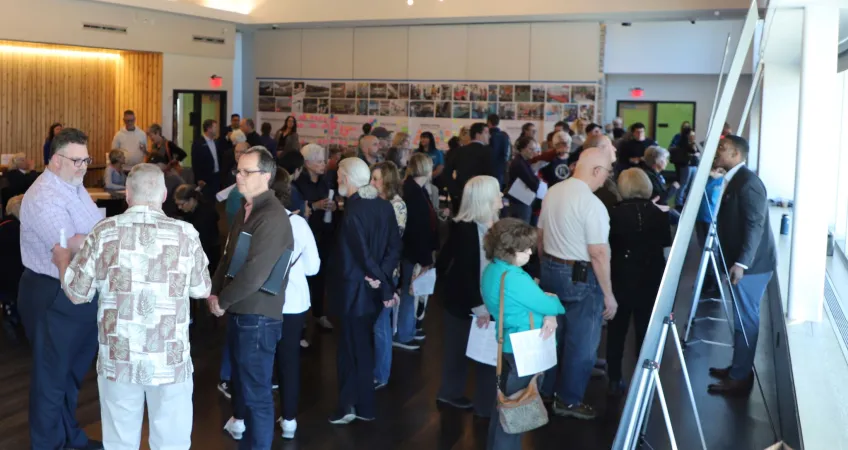 Photo of Prairie Village Community Center Campus Study public meeting on April 4, 2024. Guests look at boards with potential site configuration plans and talk with other guests and representatives from partners.