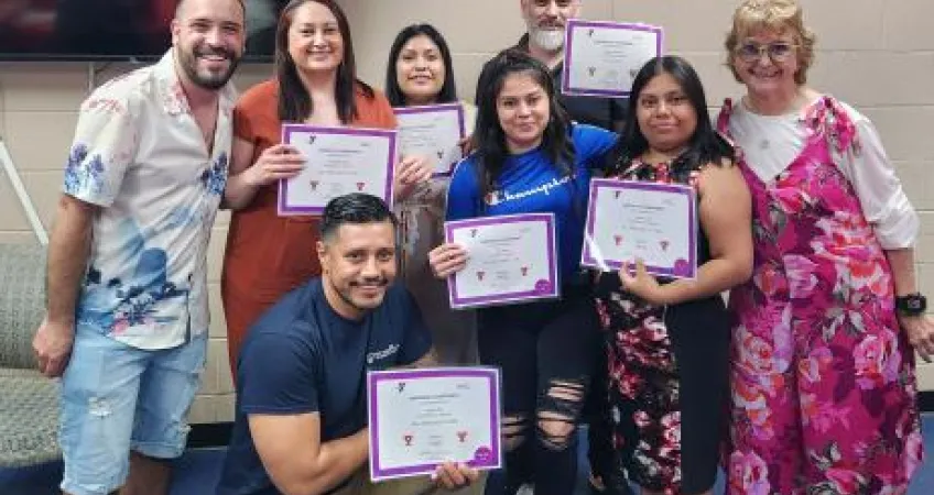 A group of eight ESL students pose for a photo with their completion certificates in a recent graduation ceremony