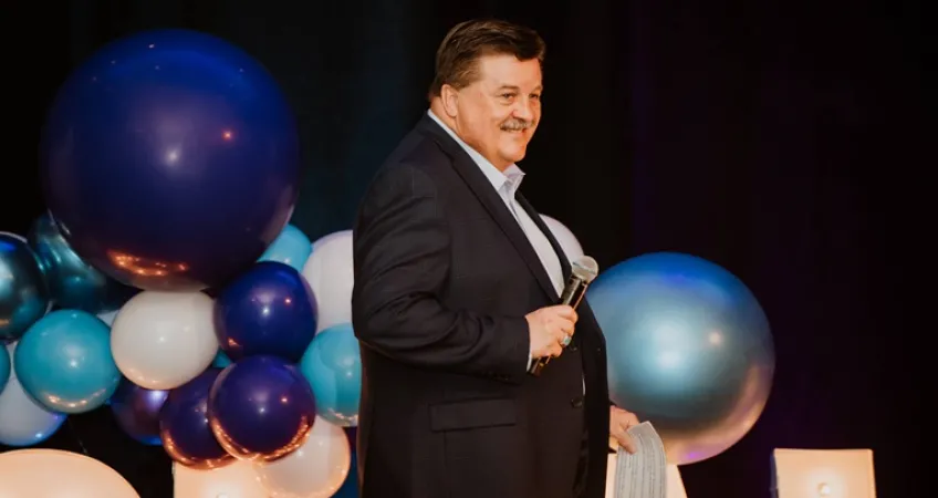 Greg Westbrook speaks on stage at a past Challenge Your Fashion fundraiser for the YMCA Challenger Program