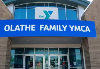 Exterior photo of the entrance to the Olathe Family YMCA. Image shows Y logo sign and large blue sign that say "Olathe Family YMCA."