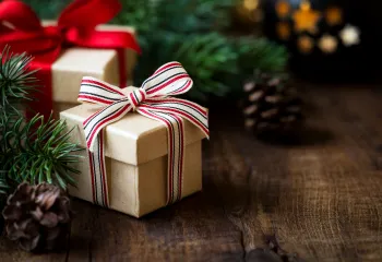 Wrapped gifts surrounded by pine tree branches on a wooden table.