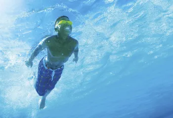 A swimmer under water wearing goggles.