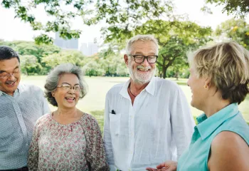 Four adults standing outside talking to each other in a group/