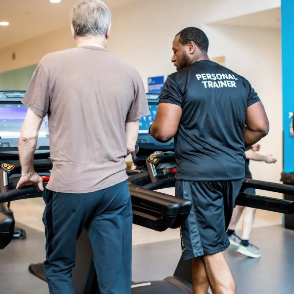 Y personal trainer coaching Y Member on treadmill.