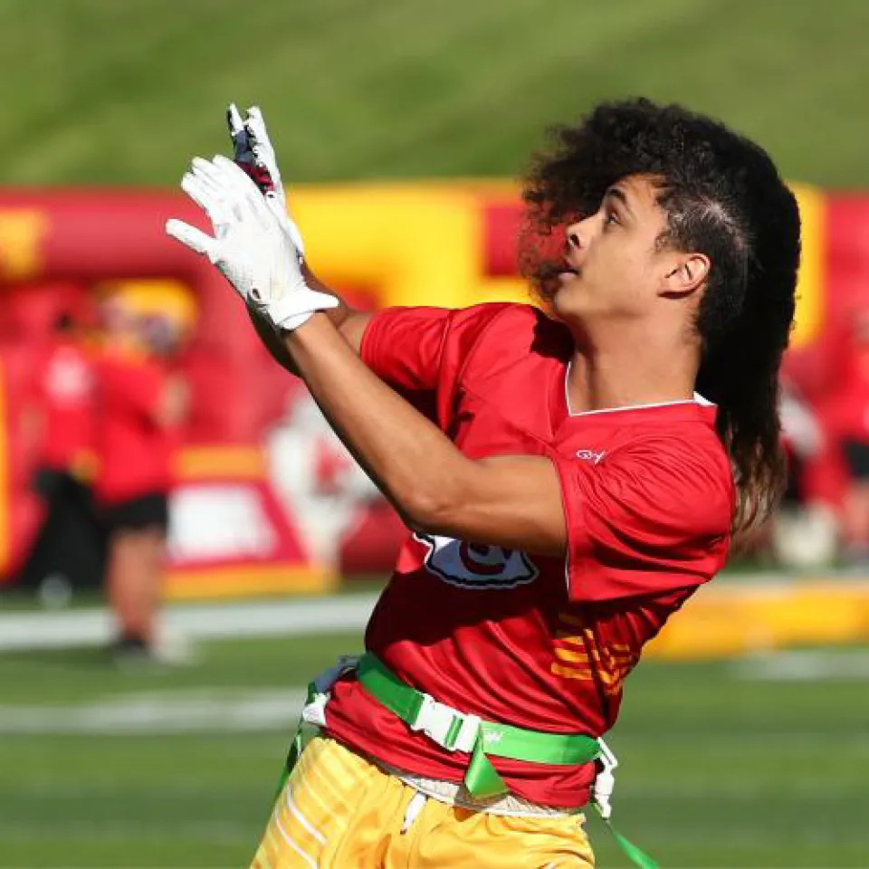 Football player with hands out about to catch the ball.