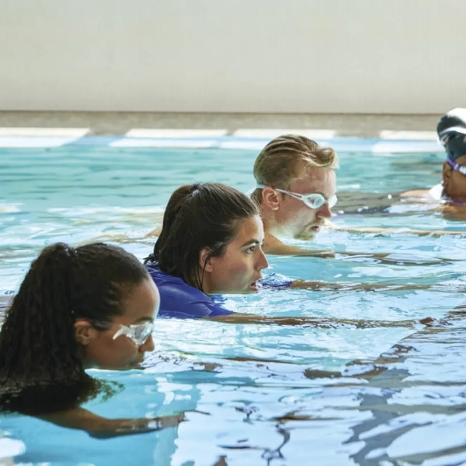 Adults hold onto a line for support while learning how to swim at a Greater Kansas City YMCA.