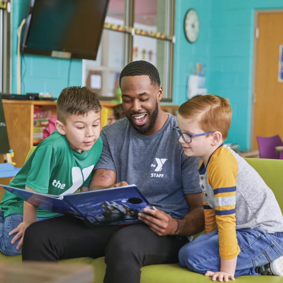 Two children are being read to by a Y staff member.