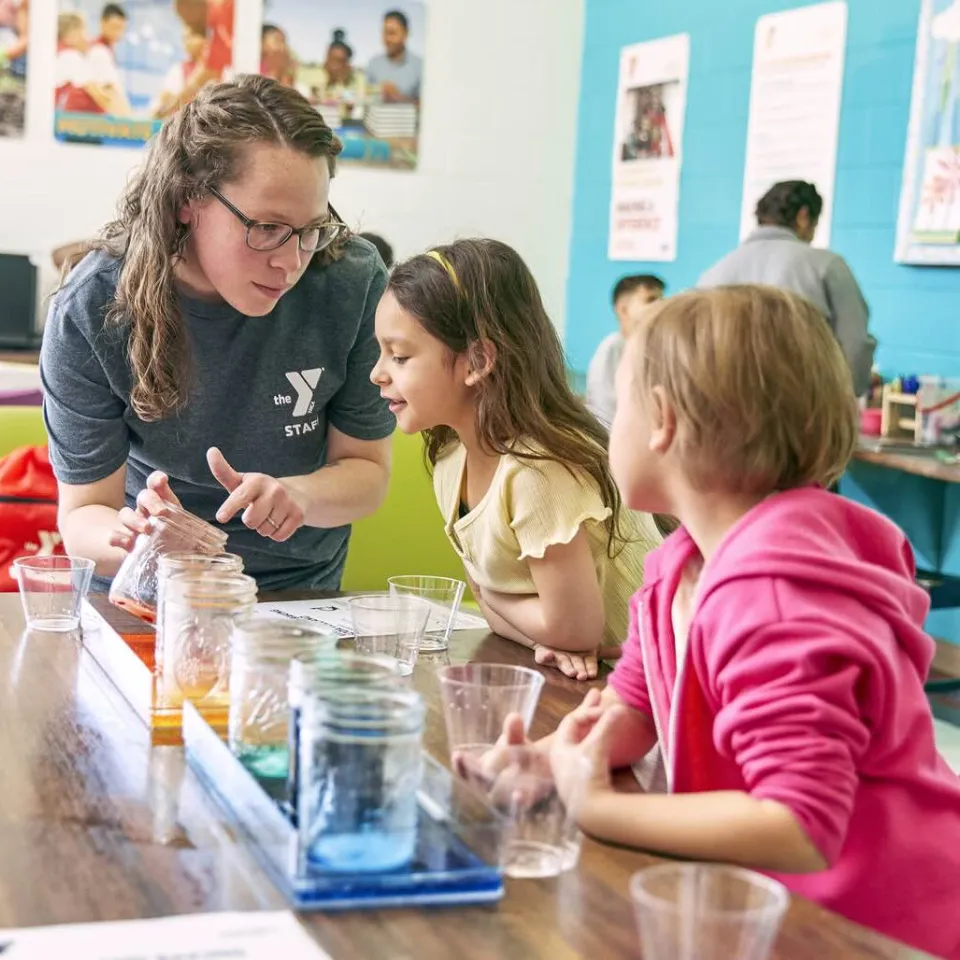 Y Instructor guiding young students through a colorful science experiment. 