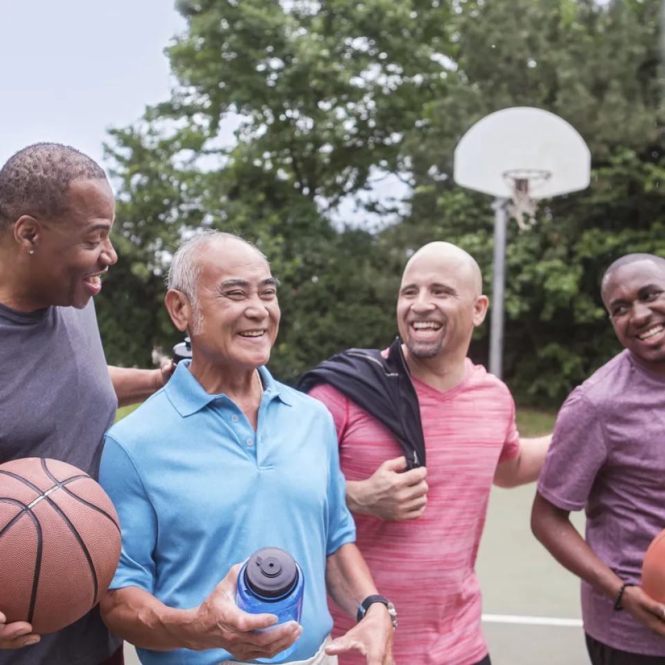 Older gentleman playing basketball with 3 other men at Kansas City YMCA basketball court.