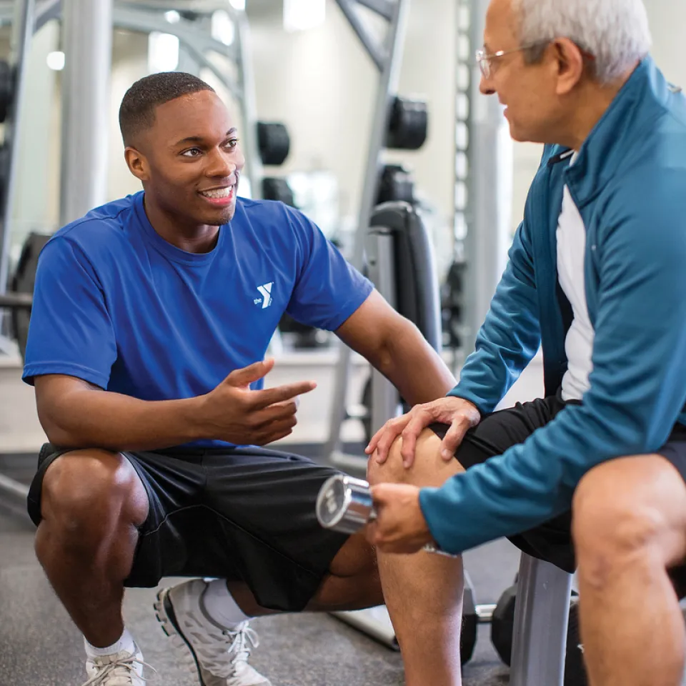 Kansas City YMCA team member coaching YMCA member on dumbbell lifting form for Arthritis Prevention