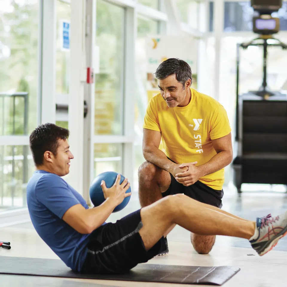 Kansas City YMCA personal trainer coaching YMCA member with weighted Russian Twists.