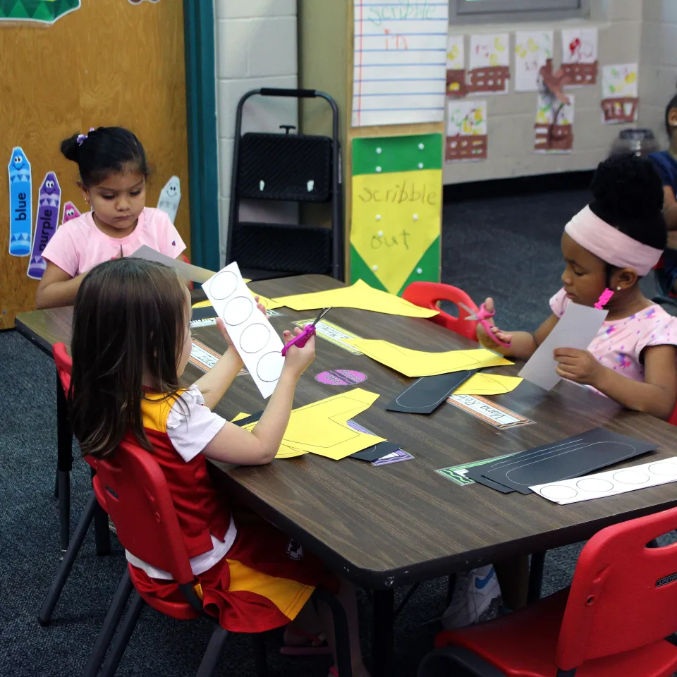 Children sit around a table cutting circles at Greater Kansas City YMCA Early Head Start Program.