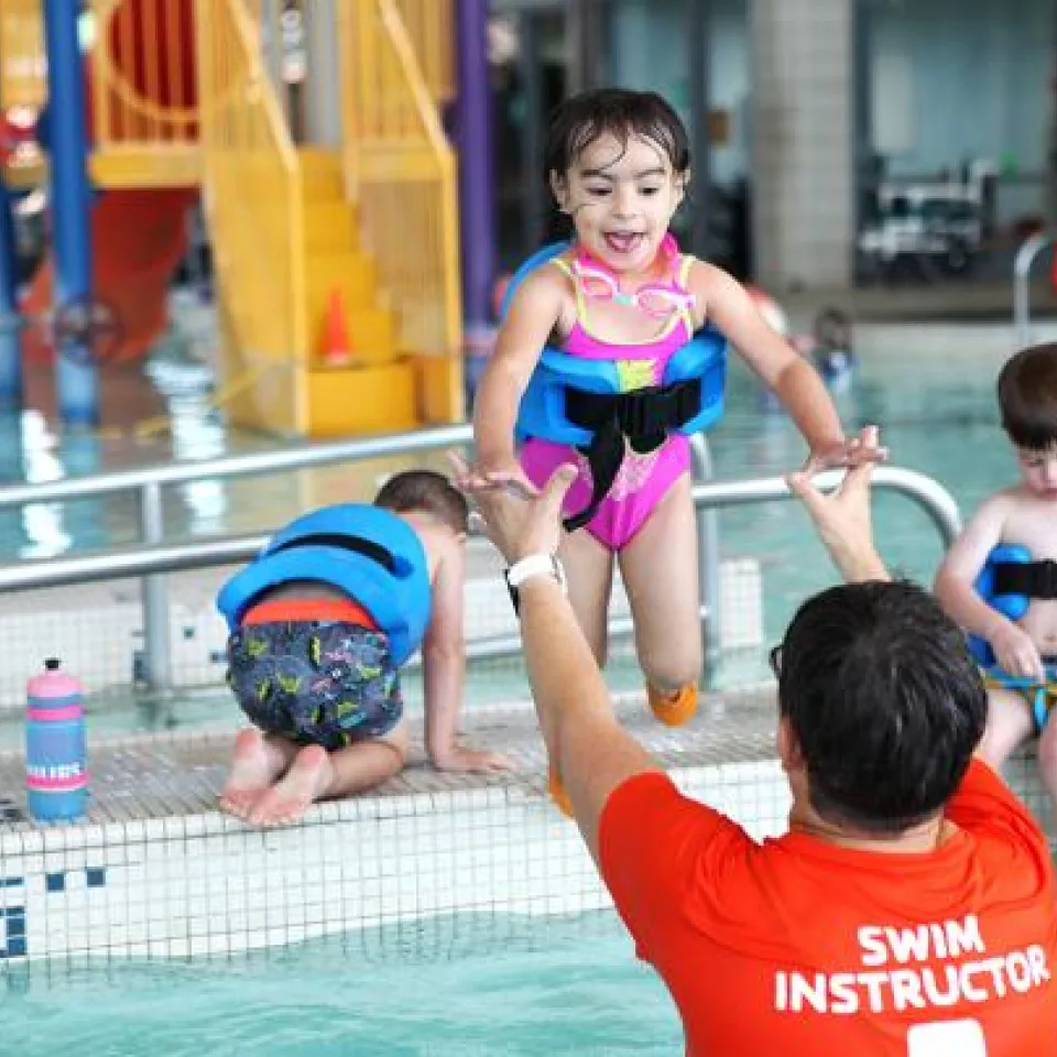 Children participating wearing floaties in swim lessons at an indoor pool with North Kansas City YMCA swim instructor.