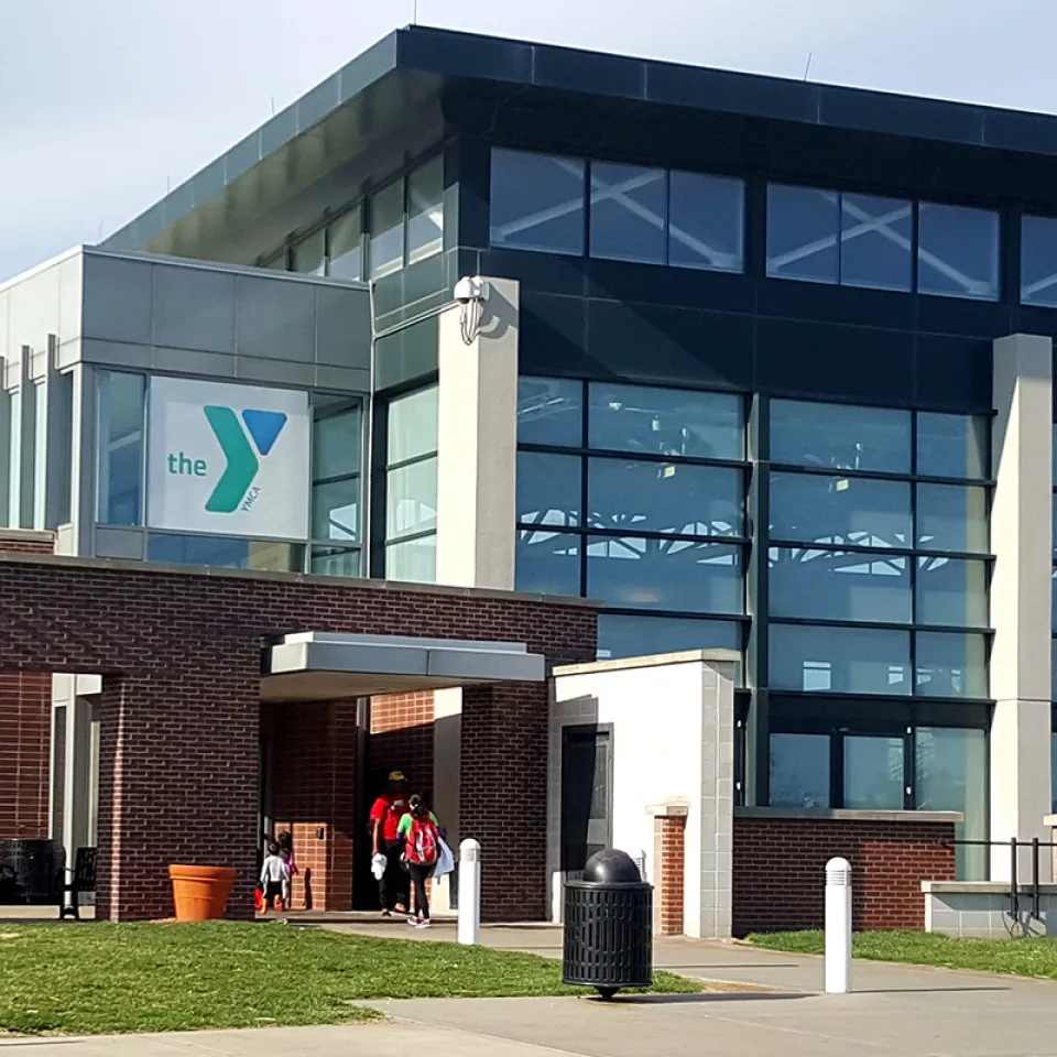 Exterior photograph of the North Kansas City YMCA. Building is made of brick on one side, floor to ceiling glass on the other, and has a bright blue YMCA logo above the entrance to the building.