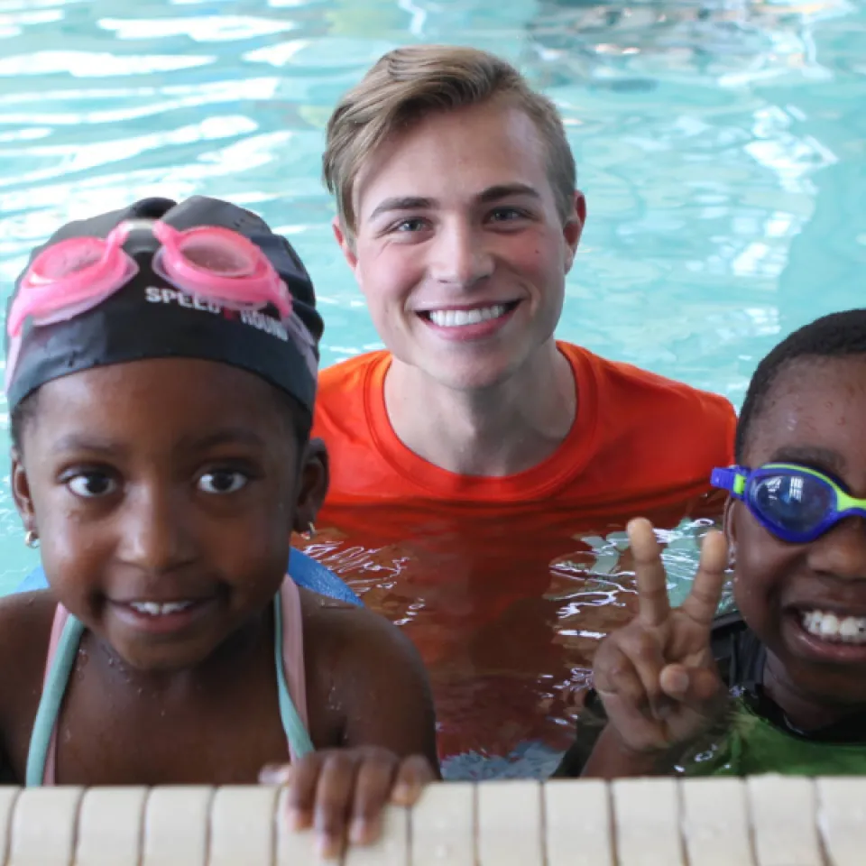 Picture of two children in the pool, pausing with their aquatic instructor.