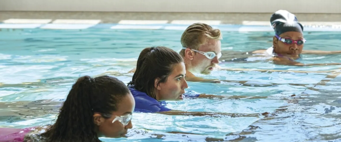 Adults hold onto a line for support while learning how to swim at a Greater Kansas City YMCA.