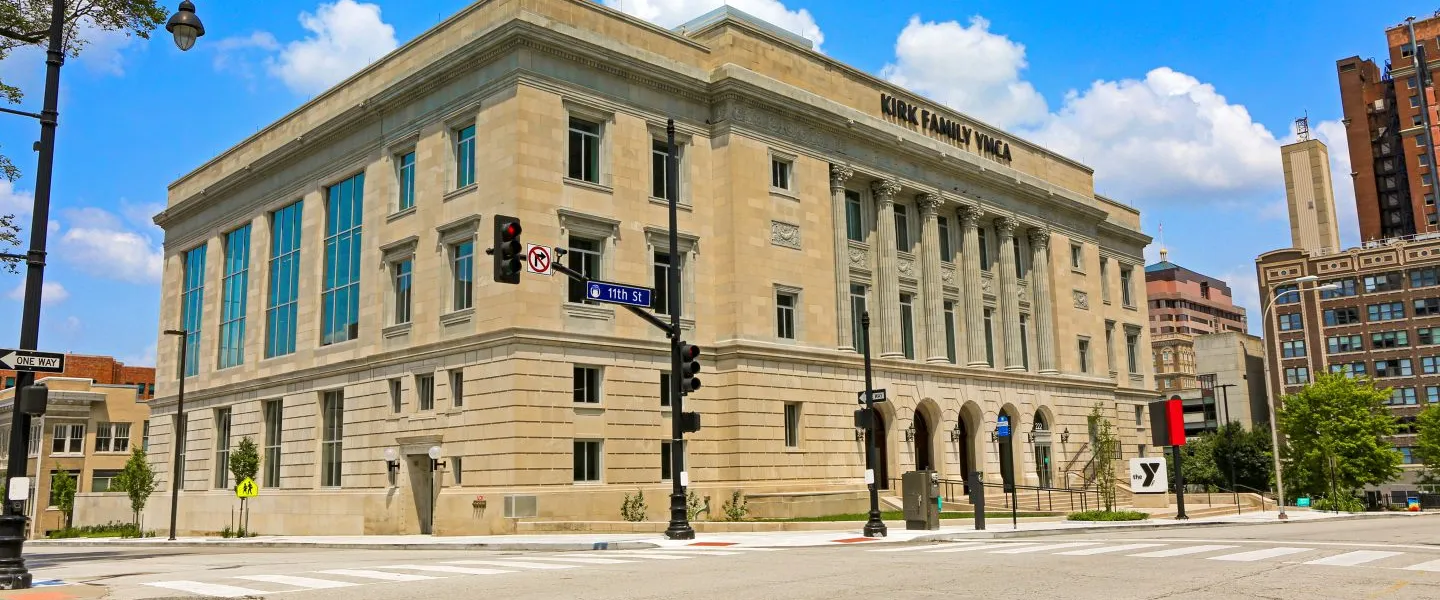 Photograph of the Kirk Family YMCA building from across the street, with kiosk visible from the east entrance of the building.