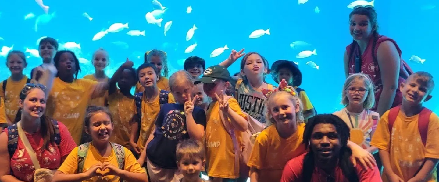 Photo of group of campers and staff on aquarium field trip with fish in the background