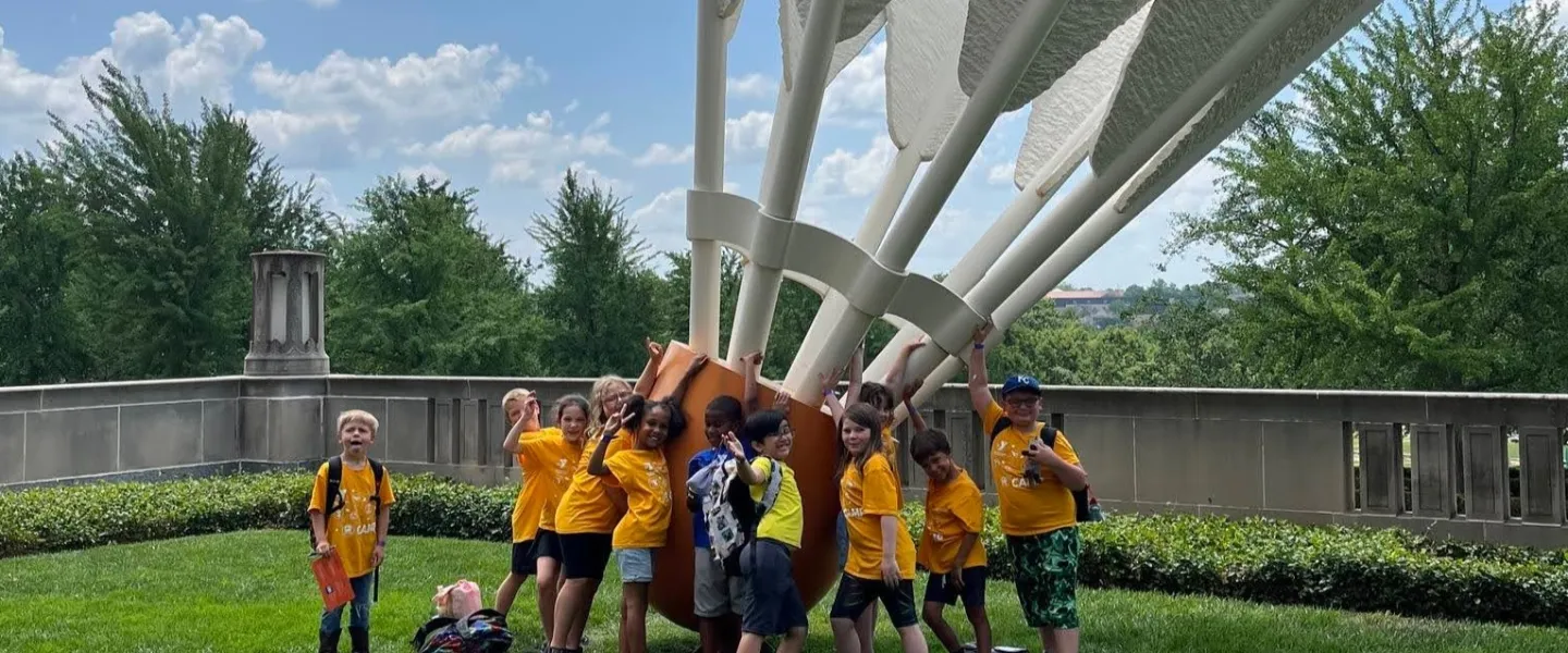 Photo of group of summer day campers standing in front of large shuttlecock sculpture