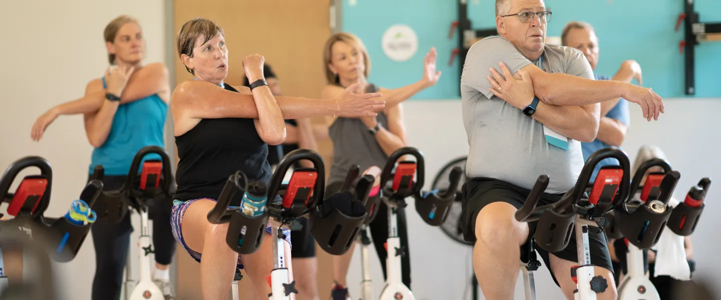 Photo of people pedaling and stretching during a group clas.s