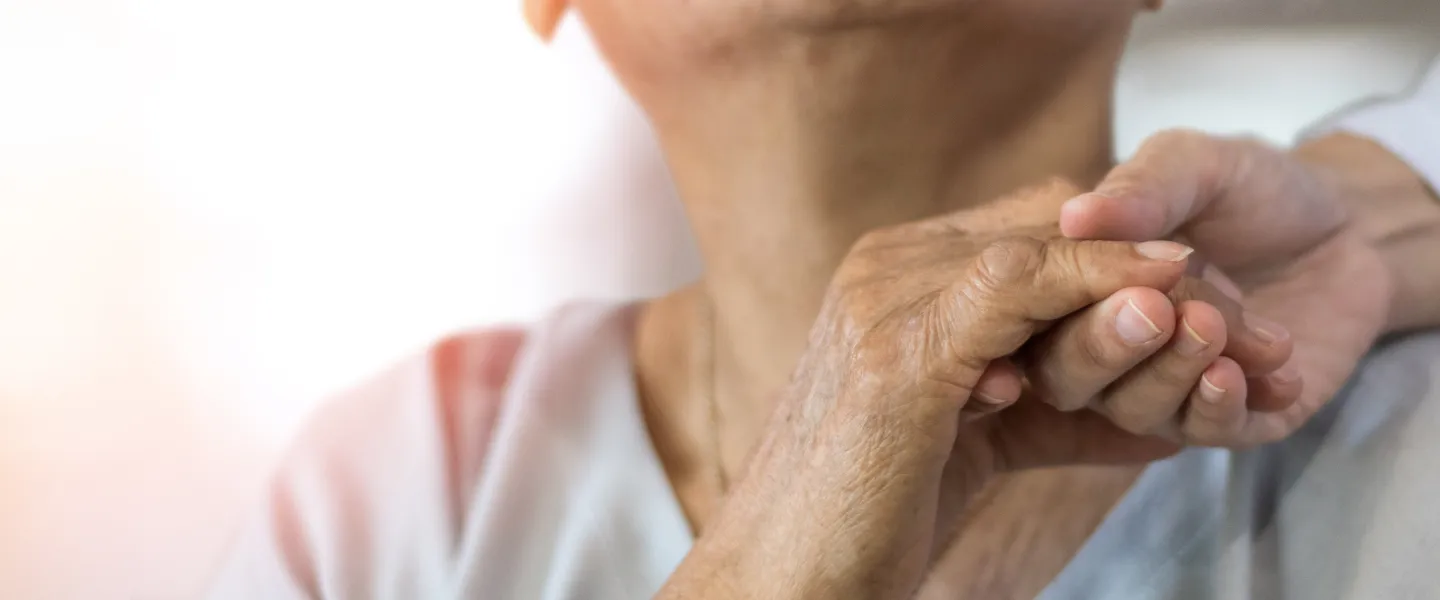 Elder person holding hand to a caregiver
