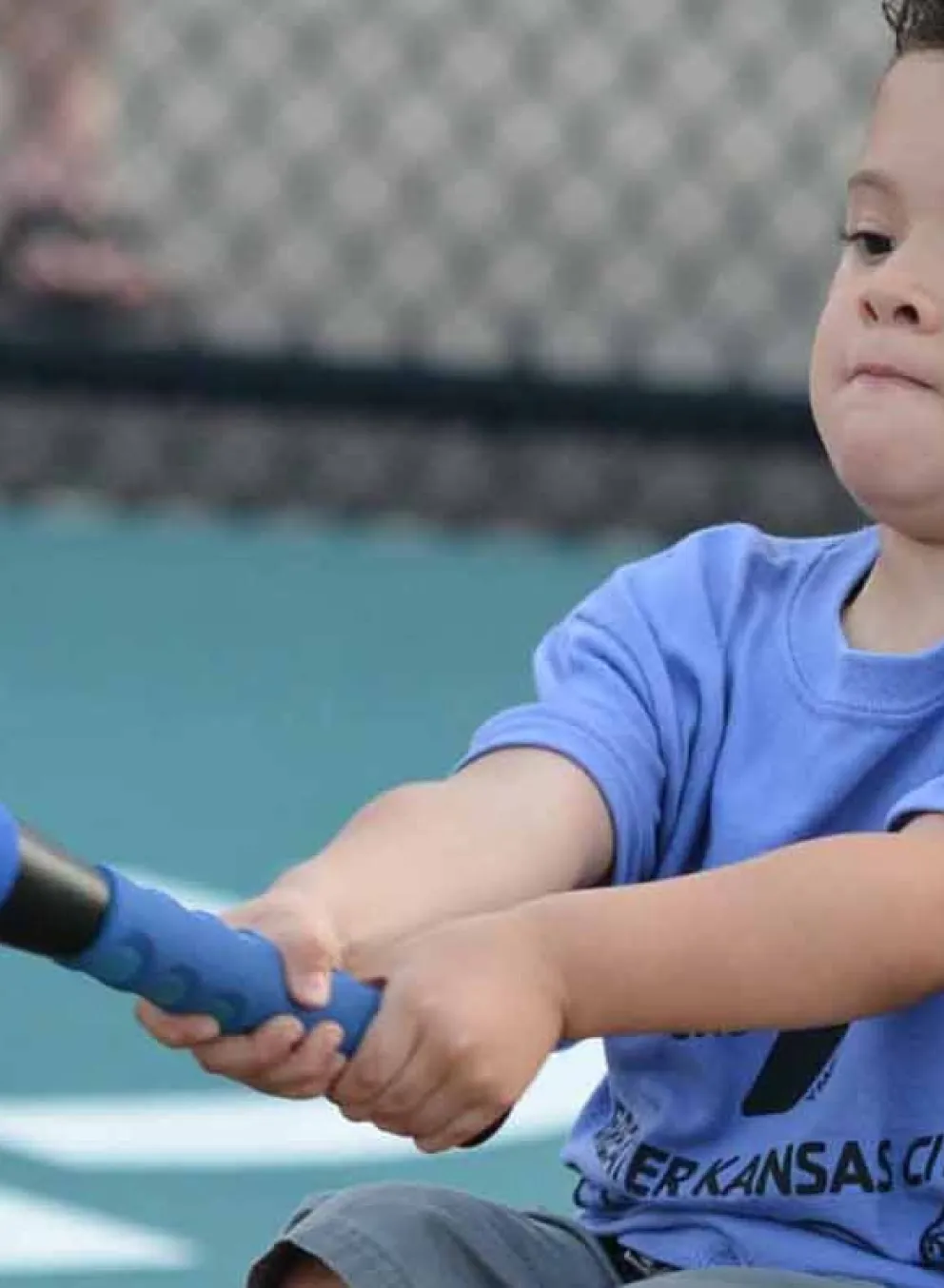 Young boy in wheelchair swings at ball on tee.