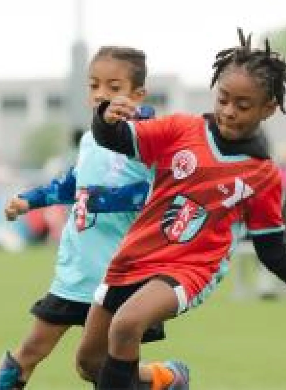 2 kids from opposing teams going after the same ball in YMCA Soccer team.